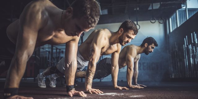 Group of men exercising push-ups in a health club.