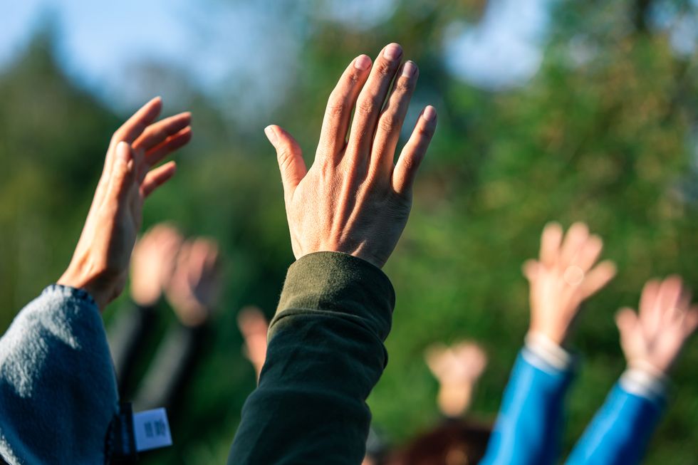 group of people with raised hands against blurred background