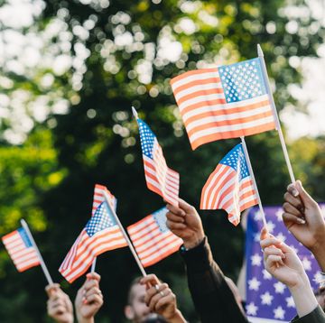 a group of people is waving small american flags at sunset