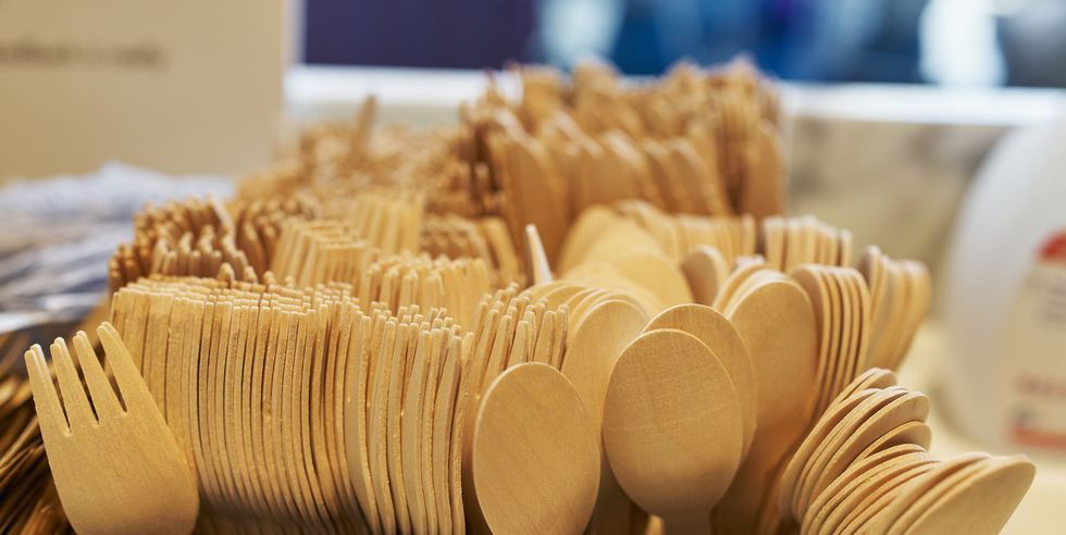 group of plastic spoons and forks in a pastry box in a row without people around, side view