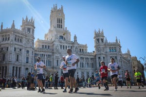 a group of runners crosses the plaza de cibeles in front of