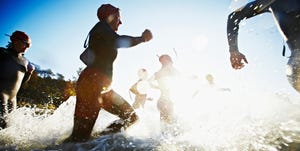 Group of triathletes running into water at sunrise