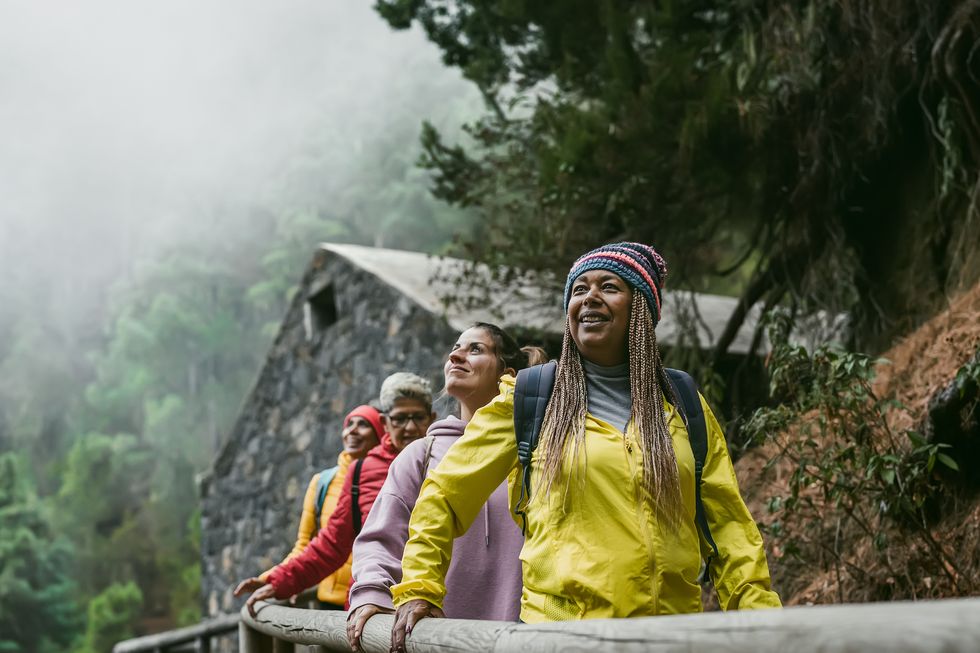 group of women with different ages and ethnicities having fun walking in foggy forest adventure and travel people concept