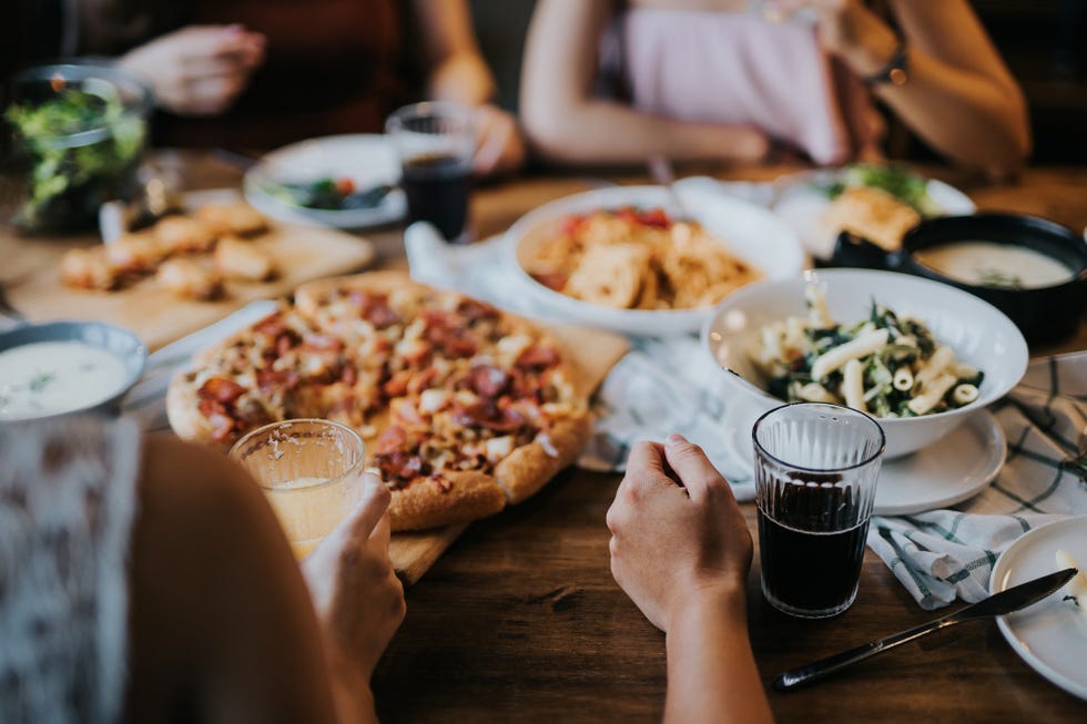 group of young asian man and woman having fun and enjoying food and drinks together during party