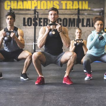 Group of young fit people lifting kettlebells in gym