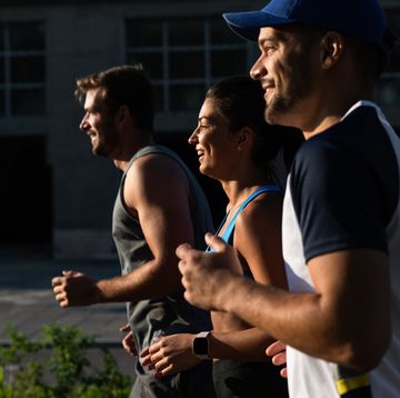 group of young friends in sports clothing running in city street in morning.