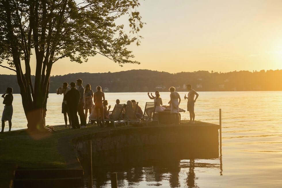group of young friends partying at lakeside during sunset, bavaria, germany
