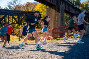 group of runners on uphill gravel path under bridge