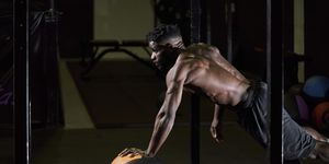man doing push ups with a weight ball inside a gym with a black floor healthy life concept