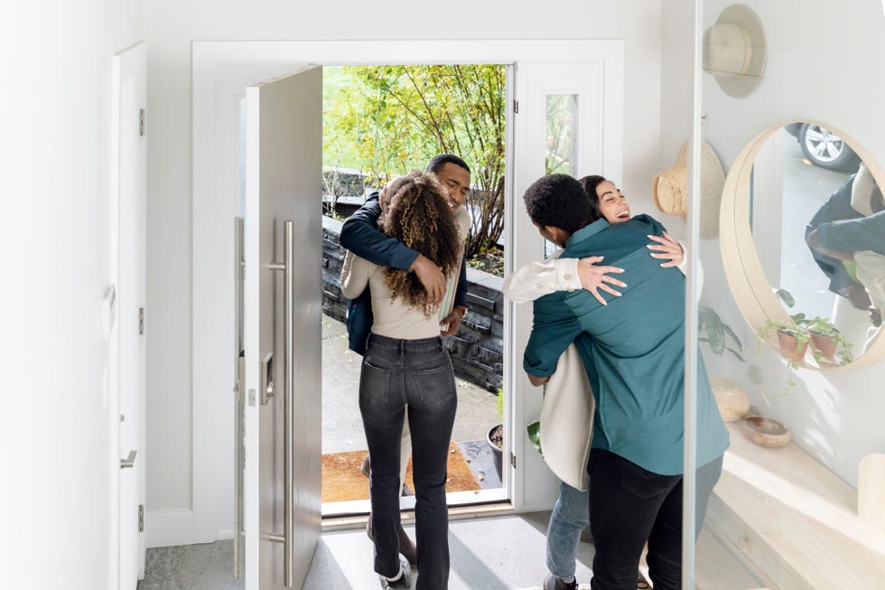 groups of friends arriving at house embracing in hallway