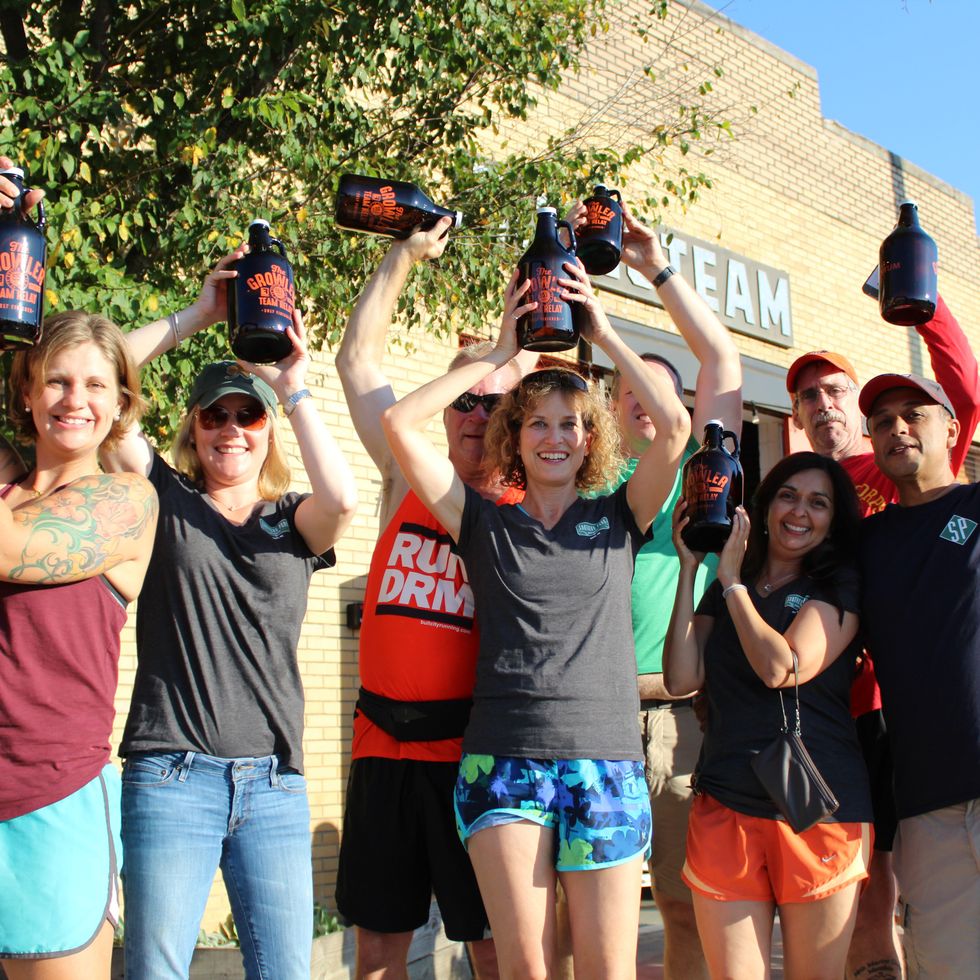 a group of runners hold up growlers at the growler relay race