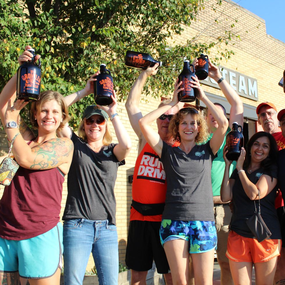 a group of runners hold up growlers at the growler relay race