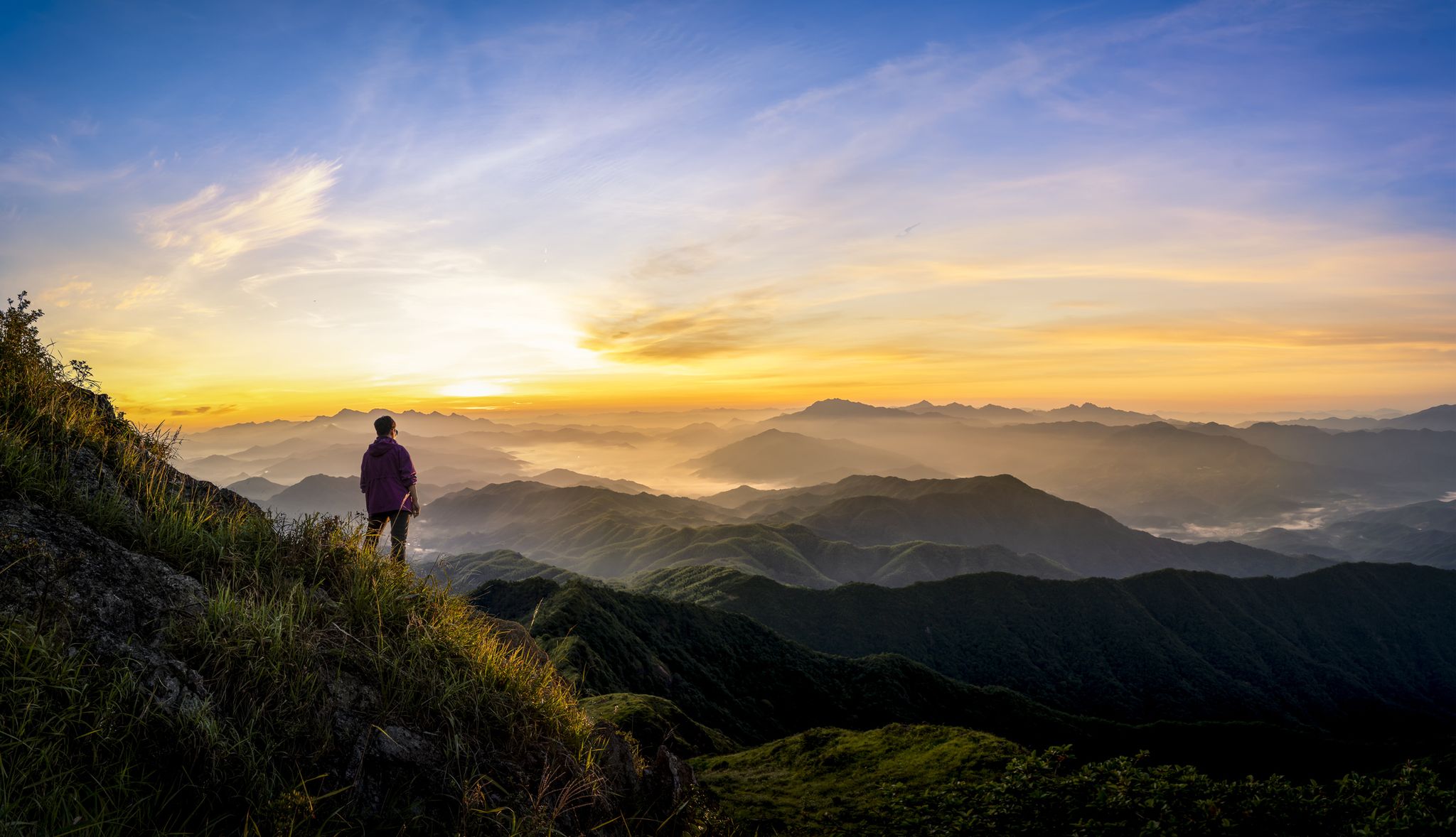 a grown woman standing on a mountain at sunrise