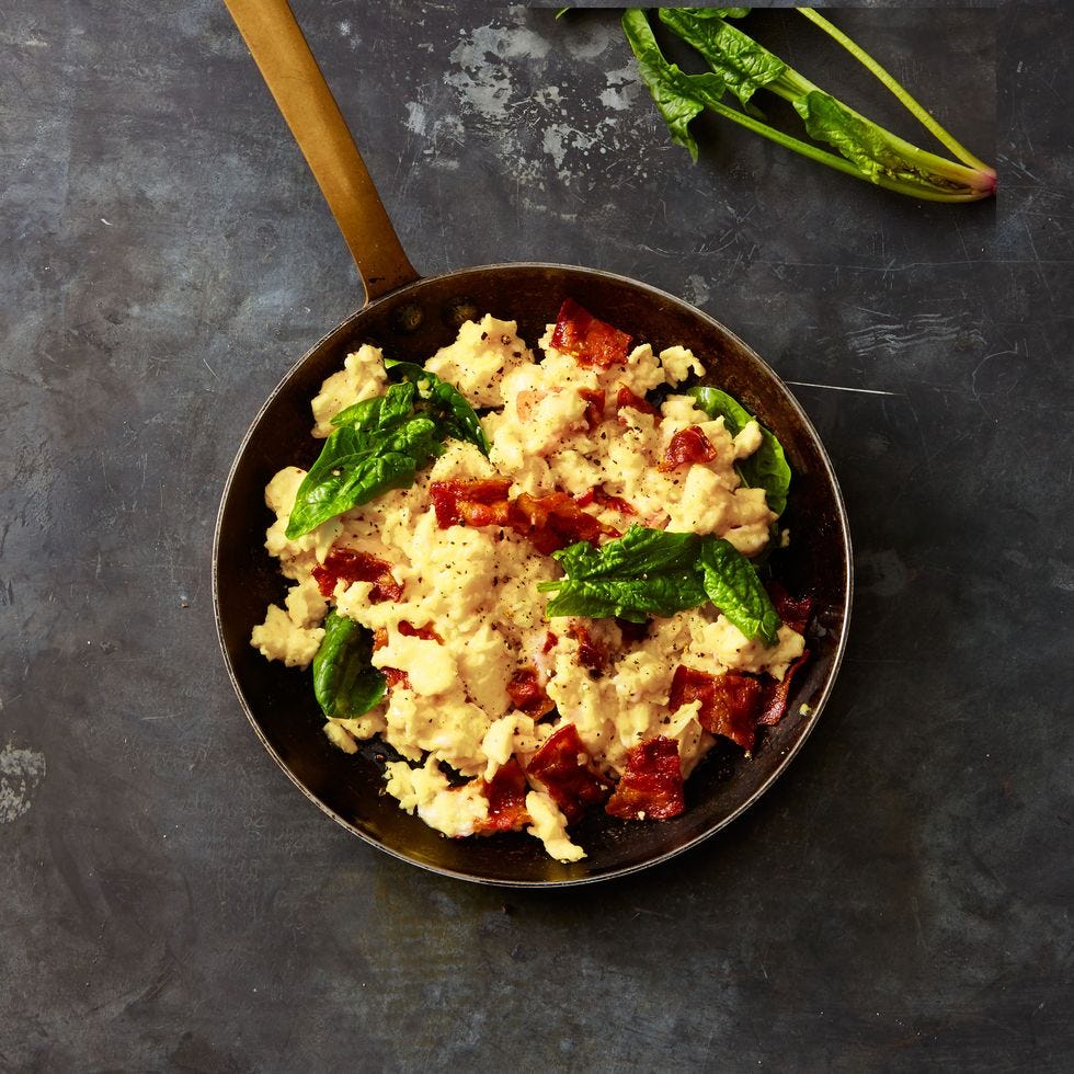 gruyère, bacon, and spinach scrambled eggs in a pan