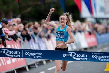 woman punches her fist in the air as she gets ready to win a running race