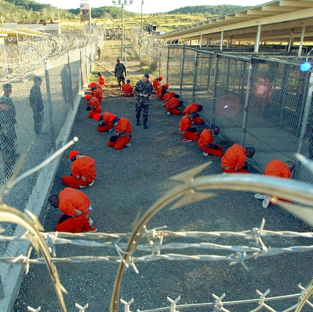guantanamo bay, cuba   january 11 in this handout photo provided by the us navy, us military police guard taliban and al qaeda detainees in orange jumpsuits january 11, 2002 in a holding area at camp x ray at naval base guantanamo bay, cuba during in processing to the temporary detention facility the detainees will be given a basic physical exam by a doctor, to include a chest x ray and blood samples drawn to assess their health, the military said the us department of defense released the photo january 18, 2002 photo by petty officer 1st class shane t mccoyus navy via getty images