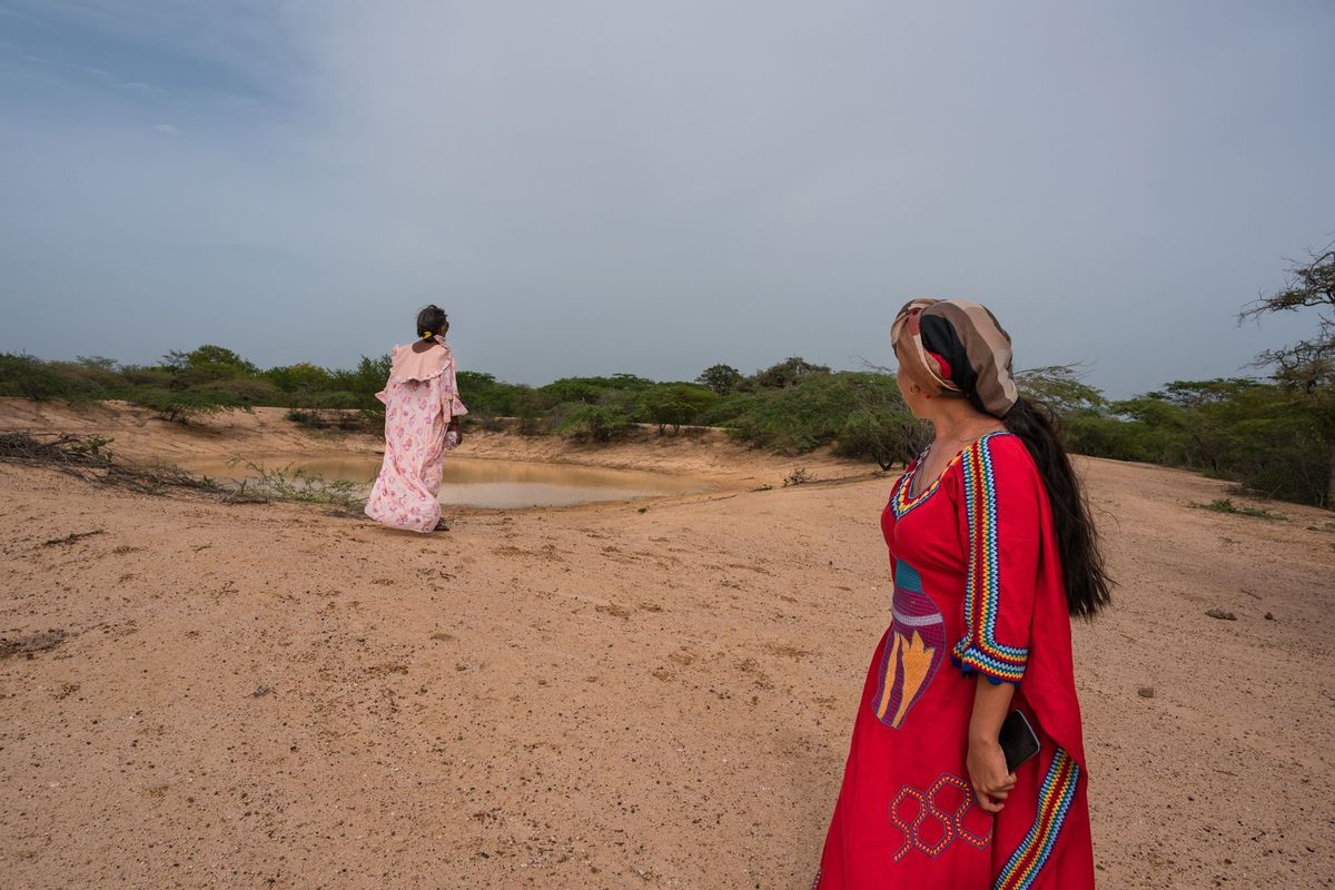 Celia Vangrieken en Yadira Martinez kijken uit over een waterplas die de Wayuugemeenschap in Parenstu in Colombia van een bescheiden hoeveelheid water voorziet