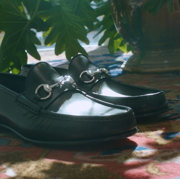 a pair of black shoes on a rug by a plant