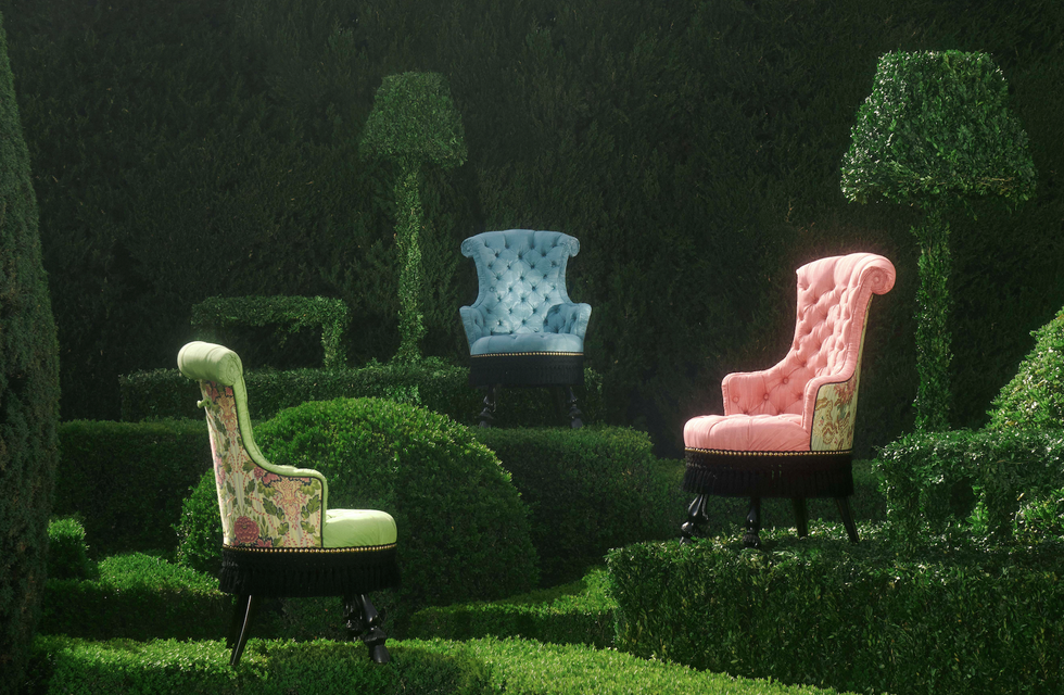 three colorful chairs in a garden next to topiaries shaped like floor lamps