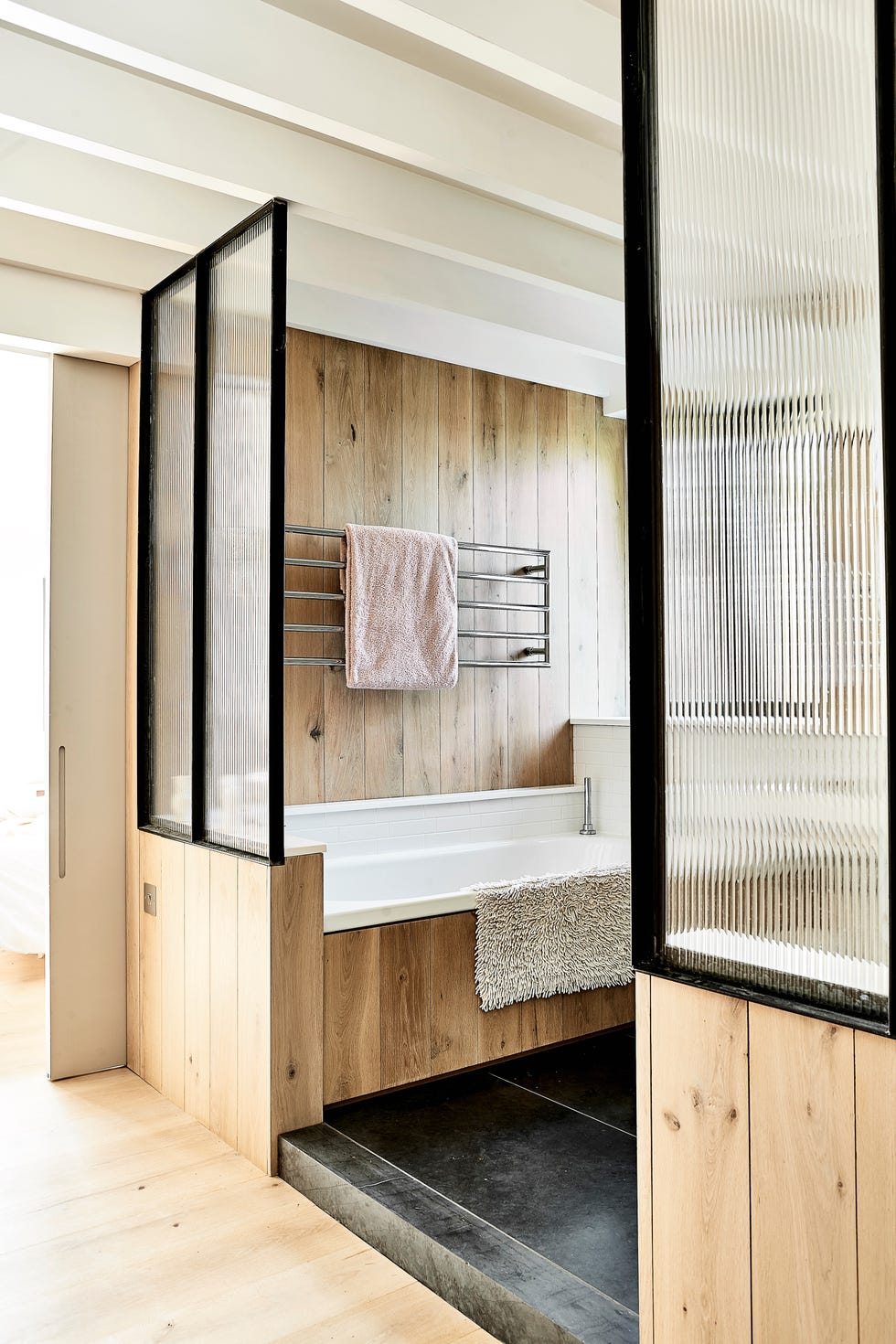 modern bathroom with timber clad bath and frosted glass panels