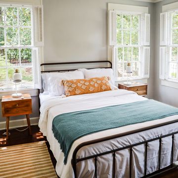 a guest bedroom with a queen sized bed and nightstand at a short term rental small cottage style house