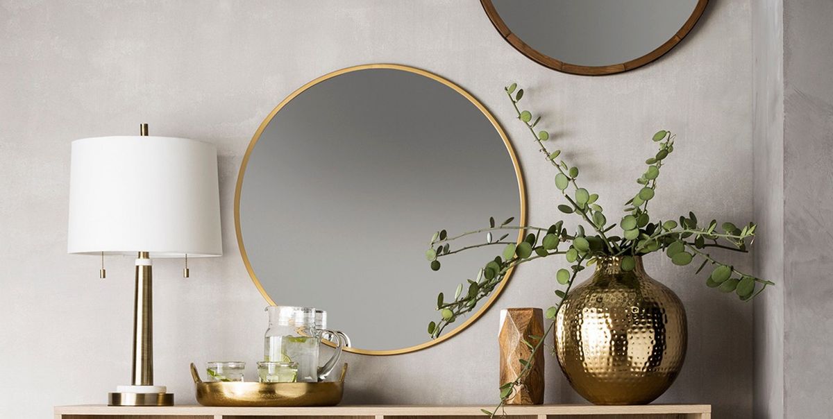a wall decorating with wooden furniture, a circular mirror, a plant and lamp