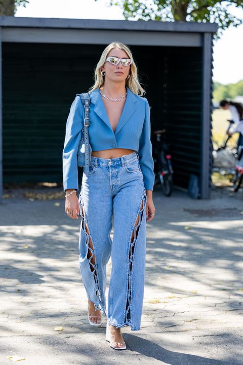 a woman wearing a blue cropped blazer and lace up baggy jeans with lucite wedge heels during copenhagen fashion week in a roundup of cute summer outfits 2023