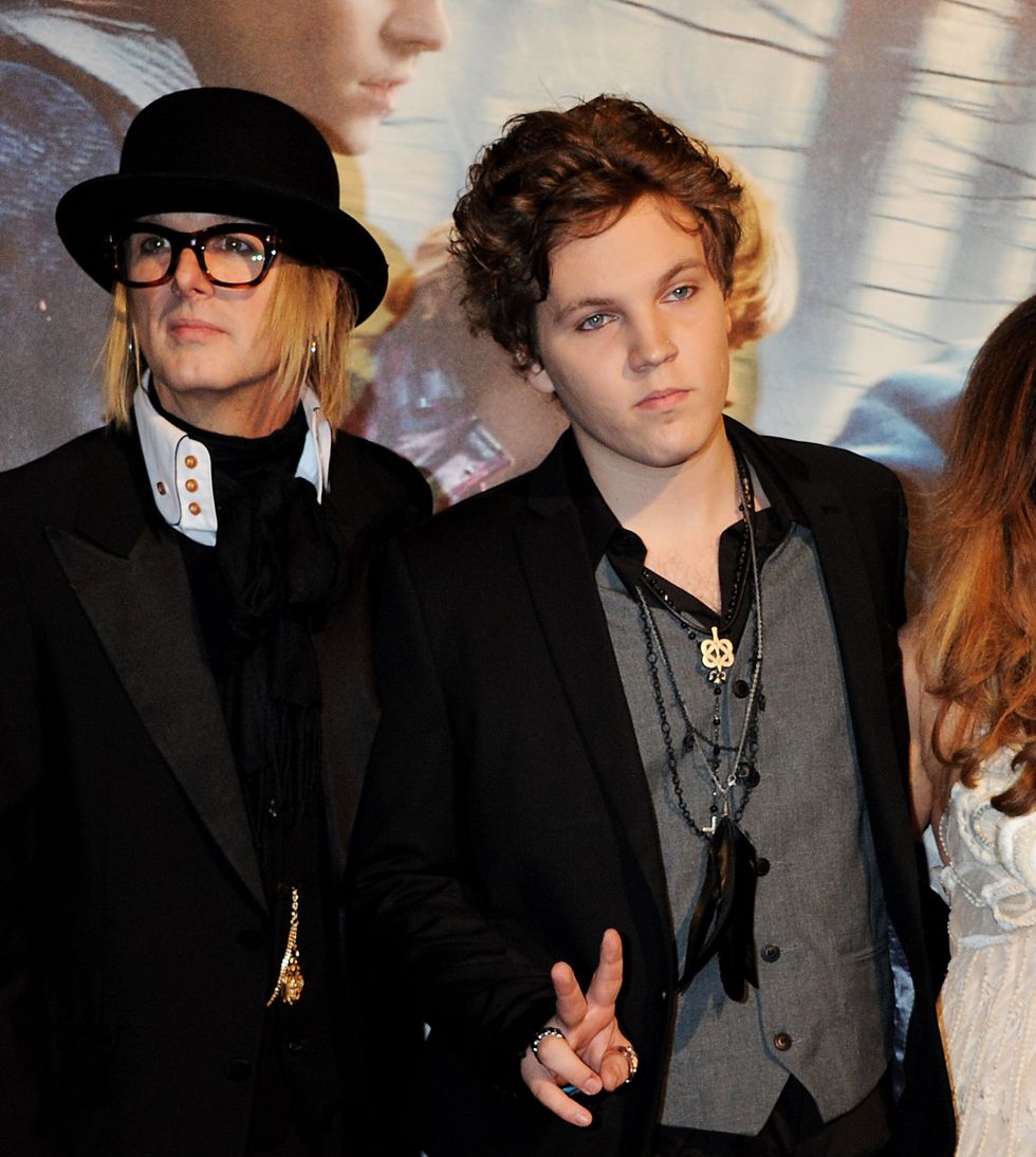 ben keough making a peace sign while standing for photos in front of a backdrop next to his mother, lisa marie presley