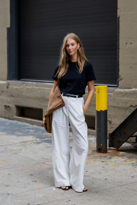 a woman wearing a black t shirt, light beige baggy trousers, and an oversize brown leather tote bag during new york fashion week in a roundup of cute summer outfits 2023