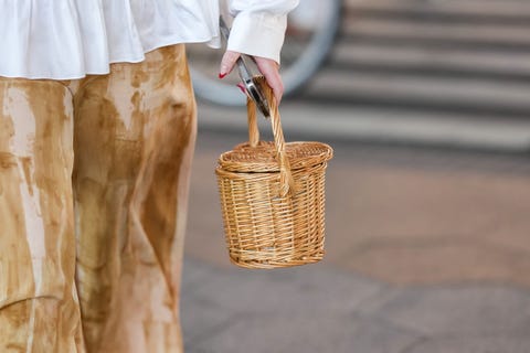 a person at fashion week carries a basket bag in a roundup of summer 2023 bag trends