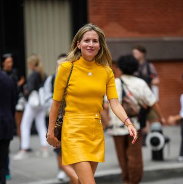 marina larroude wearing plaform heel mule shoes from her namesake footwear brand with a marigold miniskirt while crossing the street in new york city