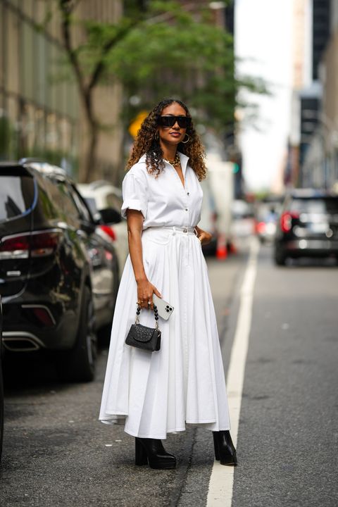 a woman wearing a short sleeve white button down and white maxi skirt with black platform heels during new york fashion week in a roundup of cute summer outfits 2023