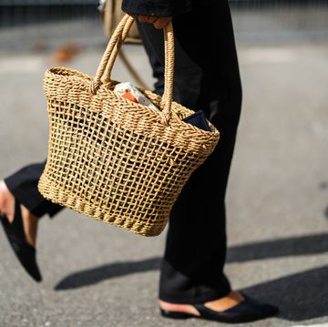 a woman at copenhagen fashion week walks with a straw bag to illustrate a story about the best straw bags of 2023
