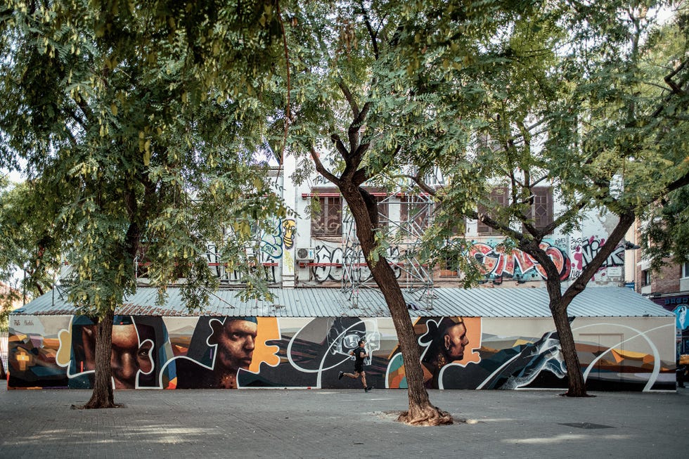 un corredor corre delante de un mural en una plaza de la ciudad de barcelona