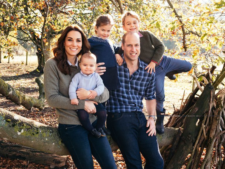 el principe guillermo con su mujer kate middleton y sus tres hijos carlota, jorge y luis, posando en un arbol en una fotografia navideña