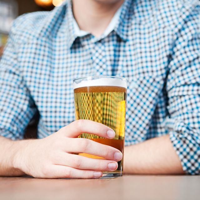 young man drinking a pint of beer in a bar