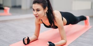gym female doing push ups exercises with elbow forearms on a pink mat in the gym