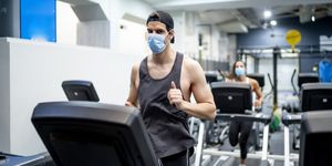 several young people running on treadmill in gym wearing face mask