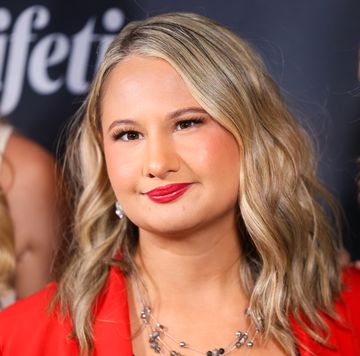 gypsy rose blanchard looks past the camera and smiles, she wears a red blazer and jewelry