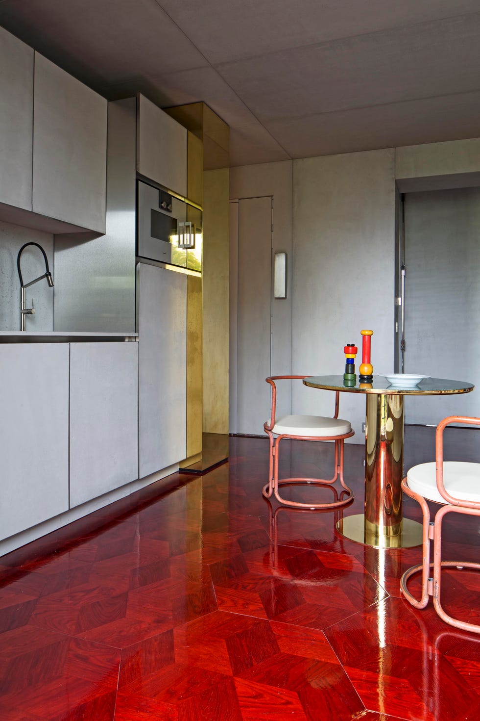 view of minimalist kitchen with rich red floor and brass table
