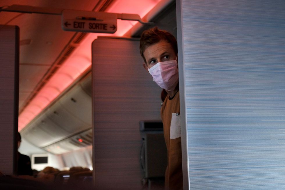 Een passagier met een mondkapje op staat tijdens een vlucht van Vancouver naar Sydney in het voorjaar van 2020 Sommige luchtvaartmaatschappijen handhaven de plicht om een mondkapje te dragen zeer strikt