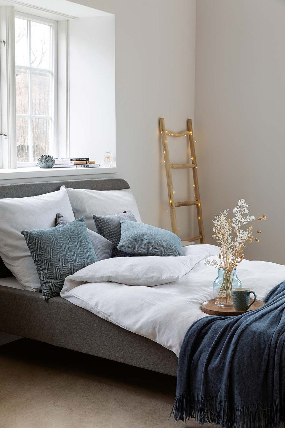 dormitorio con cama gris y edredón blanco