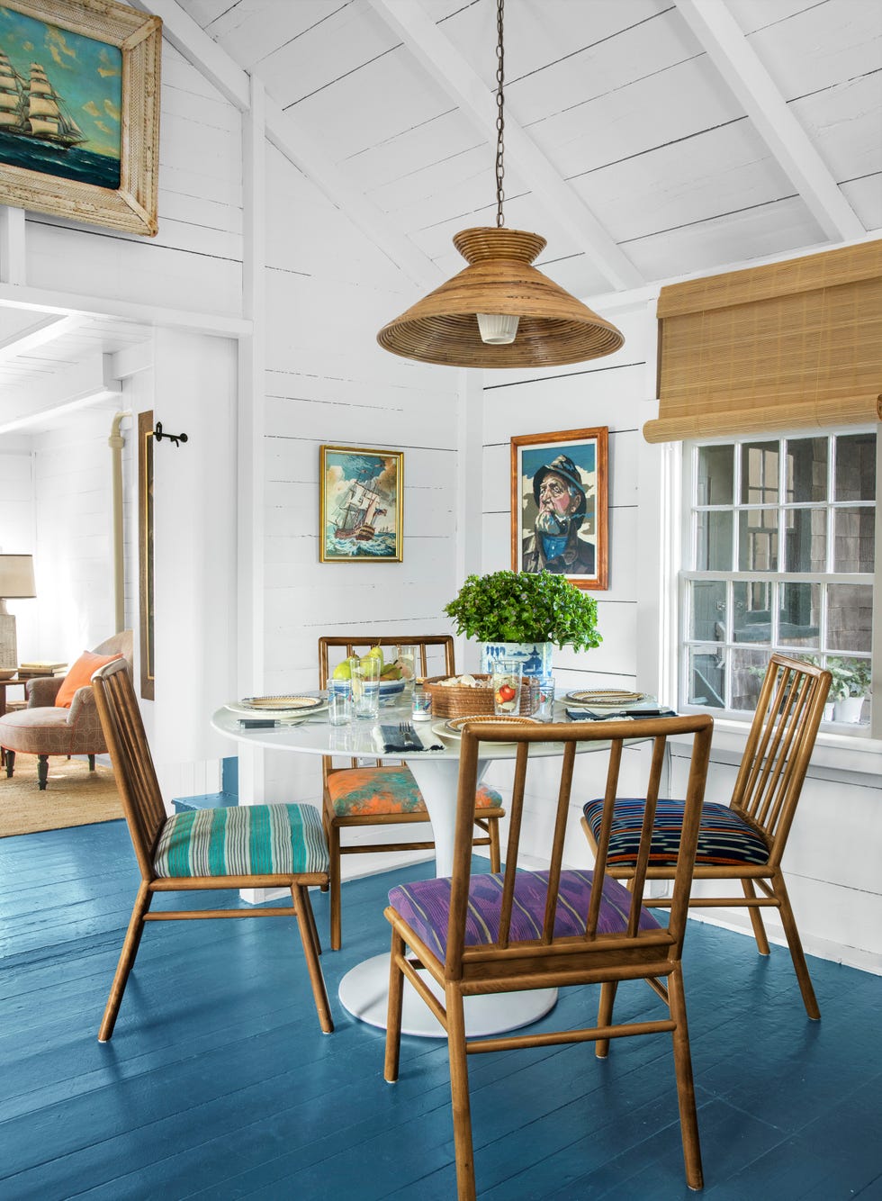 coastal dining nook with white wood floors and colorful chair cushions