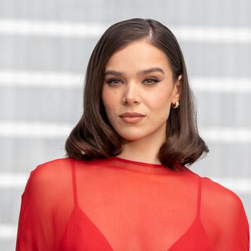 a woman in a sheer red top with a solid red bra looks at the camera