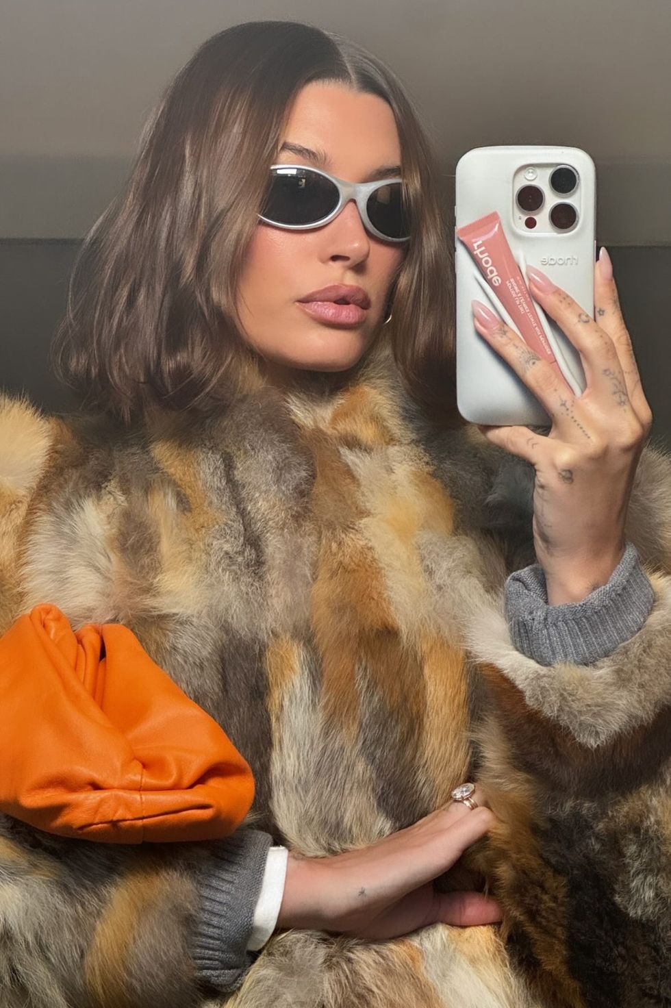a person wearing a fur coat and sunglasses taking a selfie