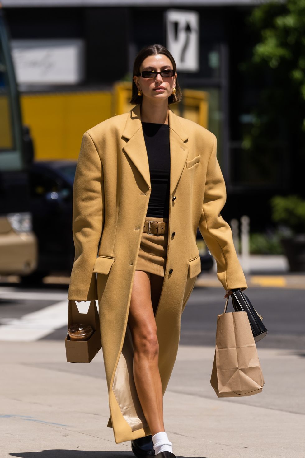 Hailey Bieber wears mini skirt and oversized Prada coat with loafers