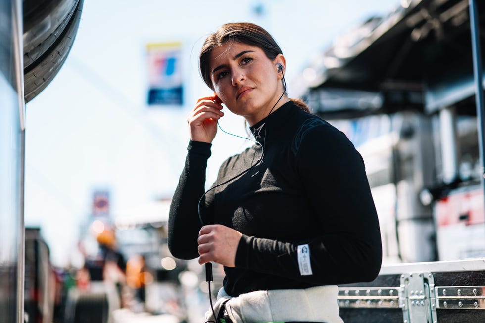 Person wearing a black outfit and earphones in a racing environment