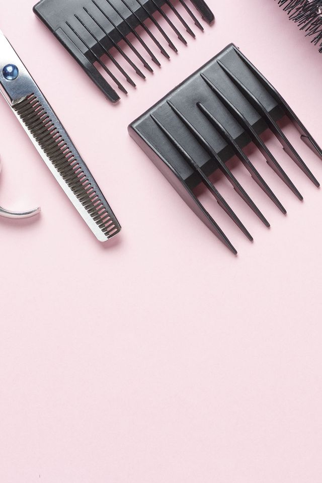 scissors and comb on a pink background, copy space