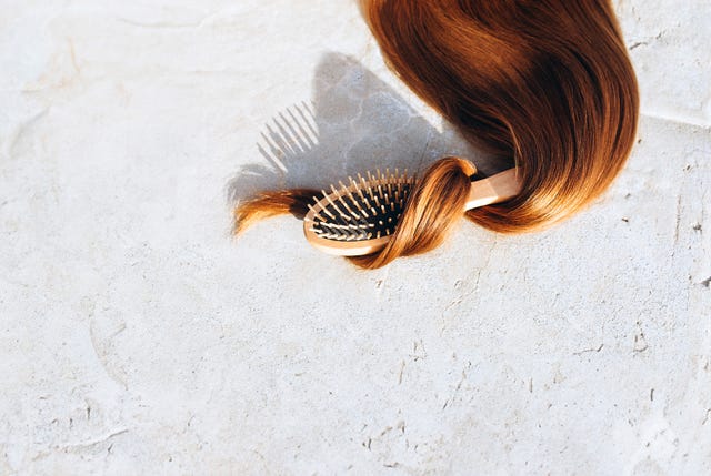 hair growth supplements still life photo of shiny hair wrapped around a hairbrush