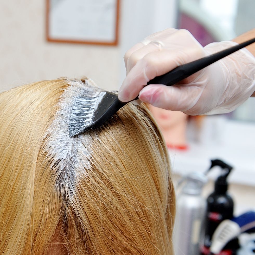 hairdresser applying dye on woman hair at salon